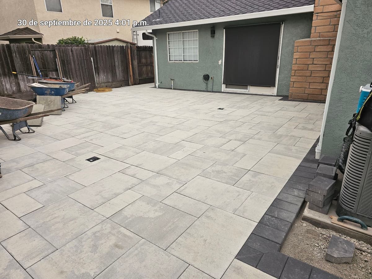 wide view of a large-format light gray paver backyard patio against a green stucco home in Stockton, California