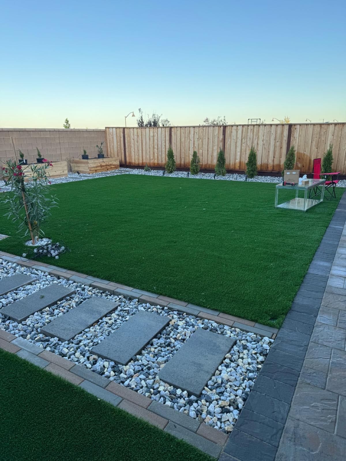 backyard artificial turf lawn bordered by a stepping stone path in white gravel in Stockton, California