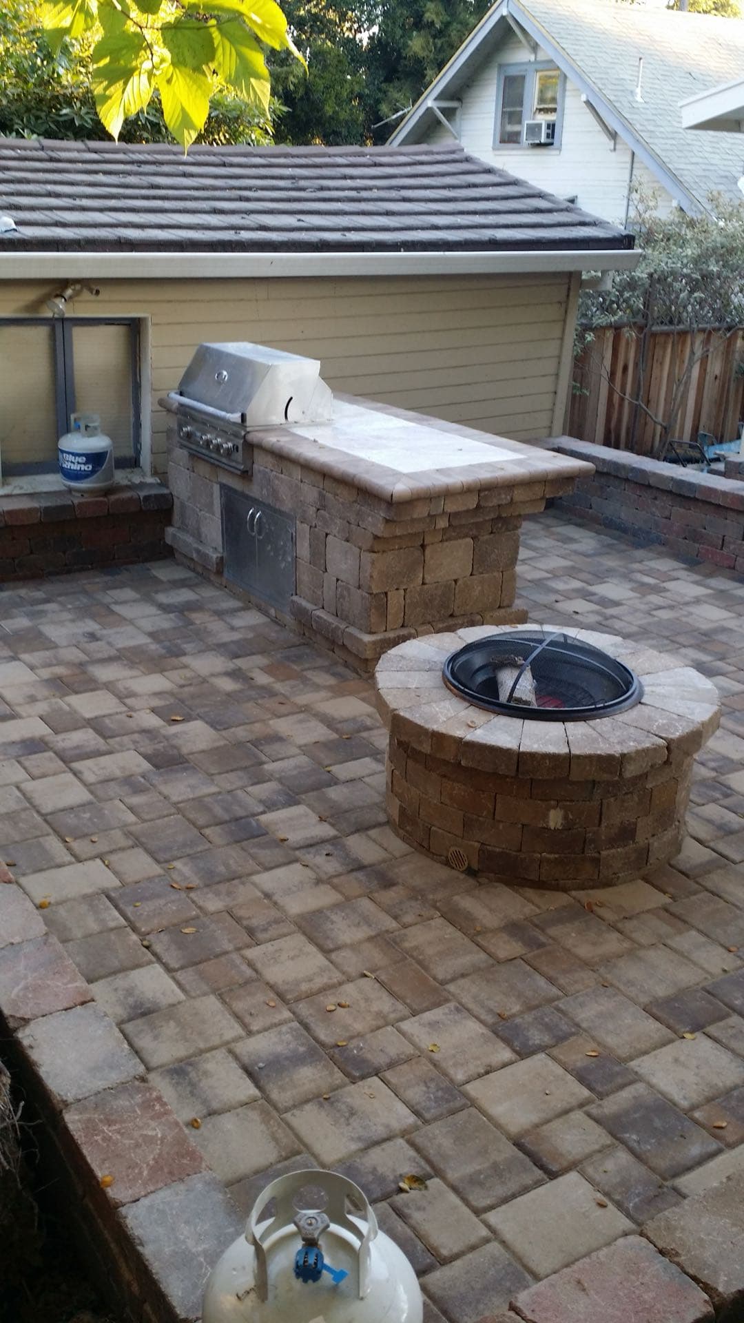 paver patio with a built-in stainless steel BBQ grill island and a round paver fire pit in Stockton, California