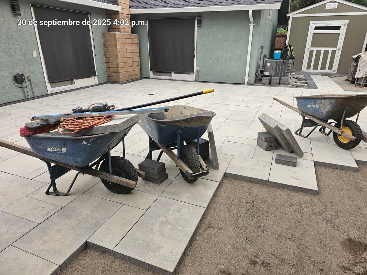 paver patio installation in progress with tools and wheelbarrows staged on the finished pavers in Stockton, California