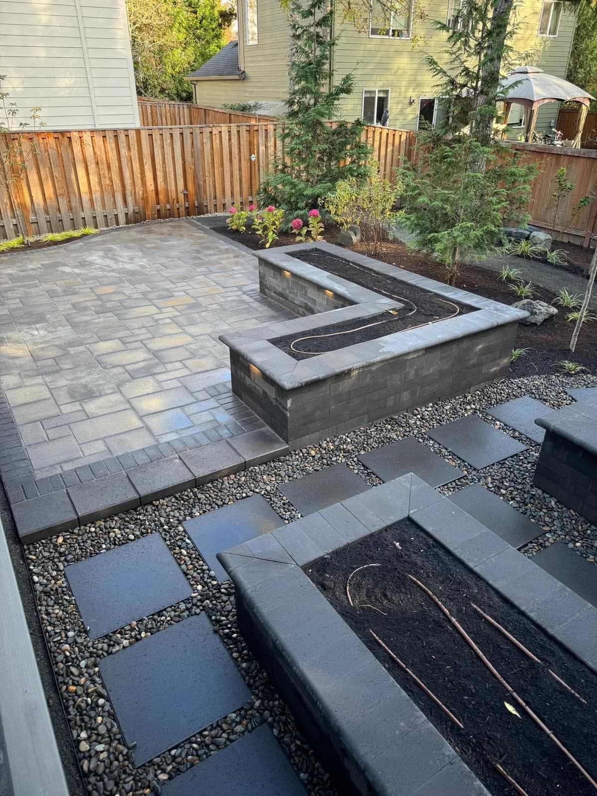 finished backyard paver patio with a custom paver seat wall, raised planter bed, and gravel stepping-stone path in Stockton, California