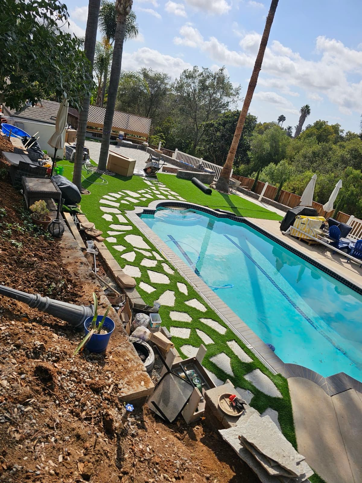 backyard pool renovation in progress with artificial turf and flagstone stepping pads under palm trees in Stockton, California
