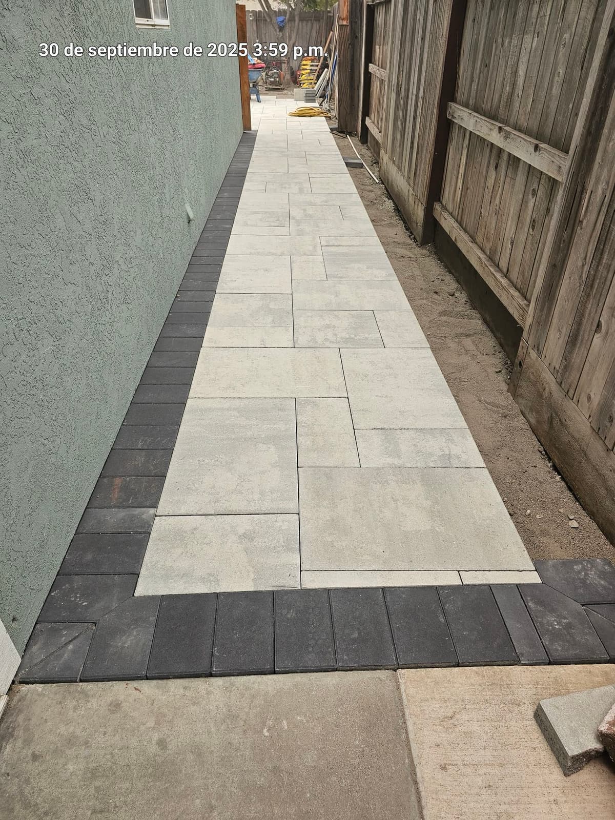 narrow side-yard paver walkway with a charcoal border under construction in Stockton, California