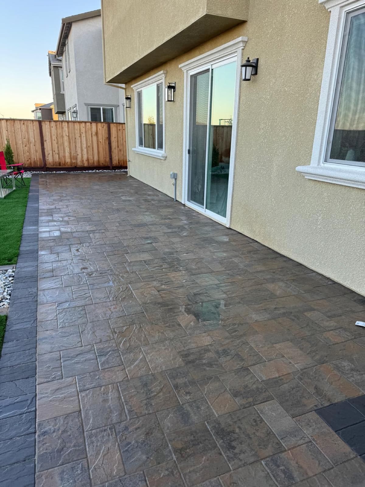 large stone-pattern paver patio along the back of a two-story home in Stockton, California