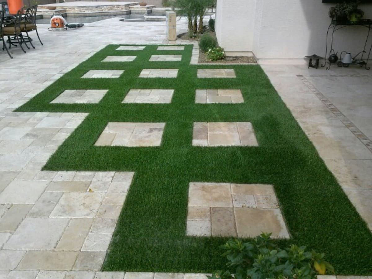travertine paver patio with a checkerboard pattern of synthetic turf squares near a pool in Stockton, California