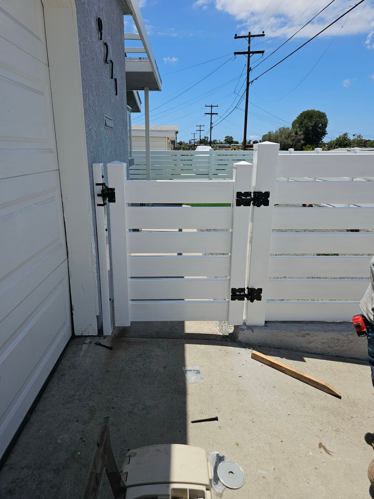 white vinyl fence gate with black hardware installed next to a garage in Stockton, California